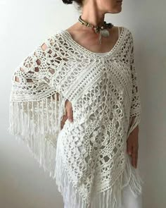 a woman wearing a white crochet shawl with tassels on her shoulders