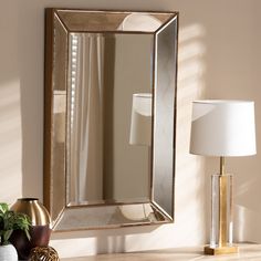 a mirror sitting on top of a wooden table next to a lamp and potted plant