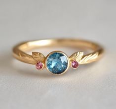 a gold ring with blue topaz and pink tourmaline stones on the side