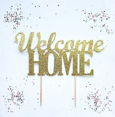 a welcome home cake topper on a white table with confetti around it