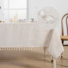 a white table cloth with tassels on it and two chairs in the background