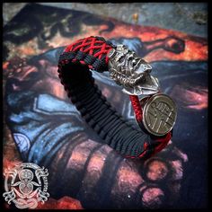 a red and black bracelet with a coin on it