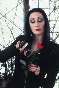 a woman with long black hair holding a rose