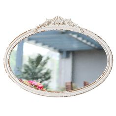 a white mirror sitting on top of a wooden table next to a tree and building