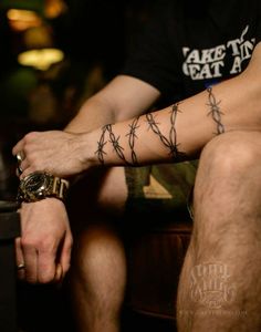 a man with barbed wire tattoo on his arm sitting in front of a suitcase and looking at the camera