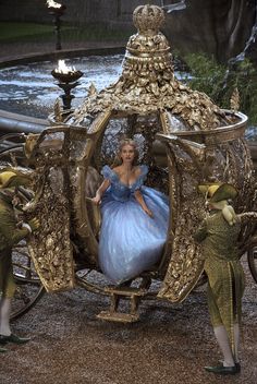 a woman in a blue dress sitting on a golden carriage