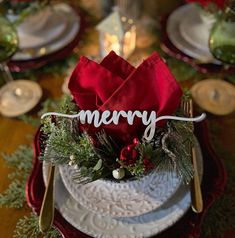 a christmas table setting with red napkins, silverware and greenery on it