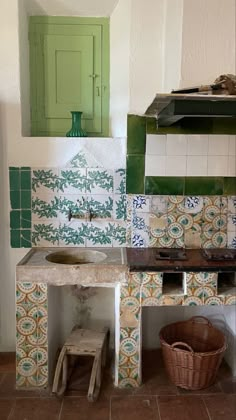 a kitchen with green and white tiles on the walls, sink and stove top oven