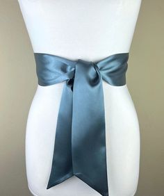 a white mannequin with a blue satin bow on it's waist and back