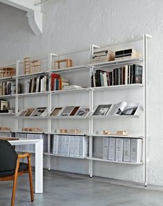 a white book shelf filled with lots of books next to a chair and computer desk