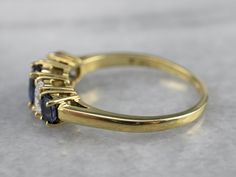 This is a timeless and attractive design for a wedding band, stacking ring, or even an engagement piece. The sapphires are deep blue, classically cut gems, perfectly matched in hue and graduating in size. Interspersed between the sapphires are brilliant oval-cut diamonds, adding some sparkle and fire to this lovely piece! Metal: 18K Yellow Gold Gem: Sapphire Gem Measurements: 6.0 x 4.3 mm, Oval Accents: 2 Sapphires, 2 Diamonds totaling .54 Carats, F in Color, VVS in Clarity Ring Size: 8 Marks: " Timeless Sapphire Baguette Cut Ring With Prong Setting, Formal Three Stone Sapphire Ring With Baguette Cut, Formal Three-stone Sapphire Ring With Baguette Cut, Three Stone Baguette Cut Sapphire Ring For Formal Occasions, Timeless Baguette Cut Sapphire Ring For Anniversary, Timeless Sapphire Anniversary Ring, Timeless Sapphire Ring With Diamond Baguette Cut, Timeless Sapphire Baguette Cut Ring With Diamond Details, Timeless Sapphire Baguette Cut Ring