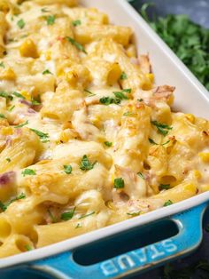 a casserole dish filled with macaroni and cheese, garnished with parsley