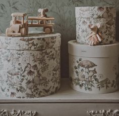 two decorative boxes on top of a dresser with toys in the back and behind them