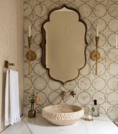 a white sink sitting under a mirror in a bathroom next to a wall mounted faucet