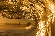 the inside of a wave in front of a cityscape with buildings behind it