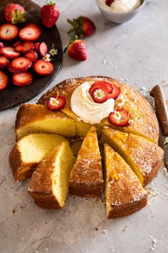 a cake with sliced strawberries and whipped cream on top, next to other desserts