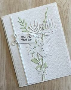 a white card with flowers on it and the words enjoy your day written in black ink