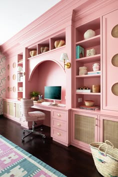 a home office with pink walls and built - in shelving, wicker baskets on the floor