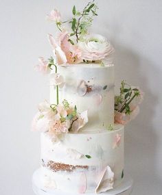 a three tiered white wedding cake with pink flowers