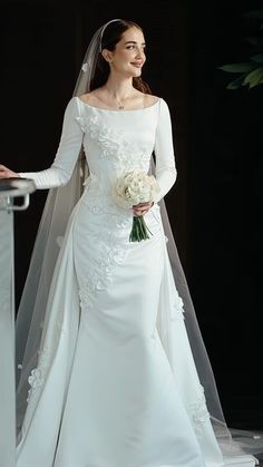 a woman in a white wedding dress standing next to a table with flowers on it