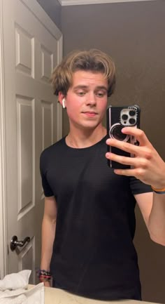 a young man taking a selfie in front of a mirror with his cell phone