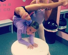 two girls are doing tricks on a chair