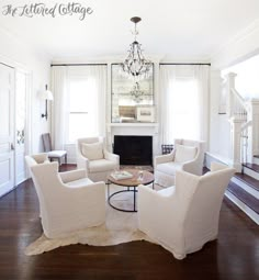 a living room filled with furniture and a chandelier hanging from the ceiling over a fire place