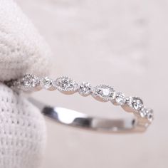 a close up view of a wedding ring with diamonds on it's side, sitting on a white cloth