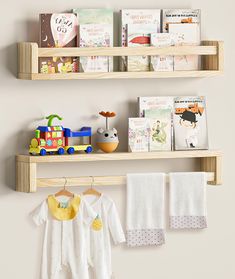 two wooden shelves holding books and baby's clothing hanging on clothes racks next to each other