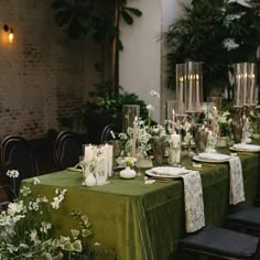 the table is set with green linens and white flowers