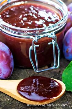 plum jam in a glass jar with a wooden spoon next to it