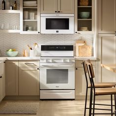 a white stove top oven sitting inside of a kitchen next to a wooden table and chairs