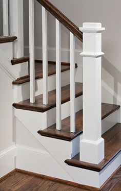 a white staircase with wooden handrails and wood flooring in a home's entryway