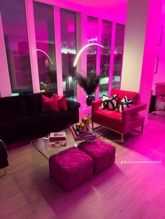 a living room filled with furniture and pink lighting