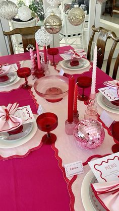 the table is set with pink and white plates, napkins, and place settings