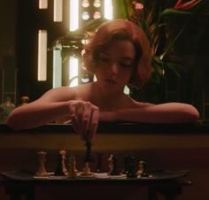 a woman is playing chess in front of a mirror with her hand on the board