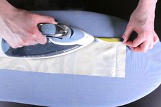 a person ironing fabric on an ironing board with a hand held electric iron