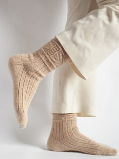 a person standing with their feet up wearing socks and pants that are knitted together