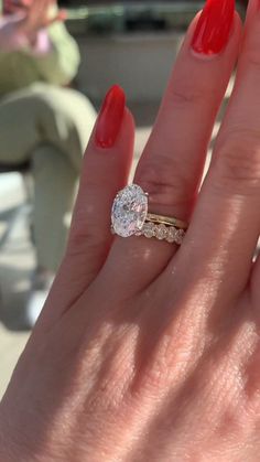 a woman's hand with red nail polish holding a diamond ring