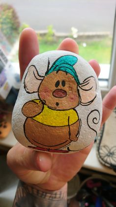 a hand holding a rock with a cartoon character painted on it