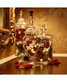 two glass jars filled with candy sitting on top of a table next to a mirror