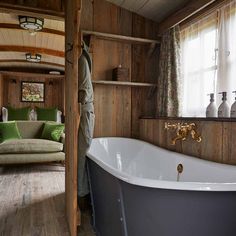 an old fashioned bathtub in the corner of a room with wood paneled walls