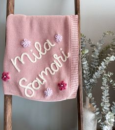 a pink towel hanging from a wooden ladder next to a potted plant and vase