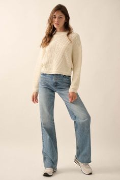 a woman in jeans and a sweater poses for the camera