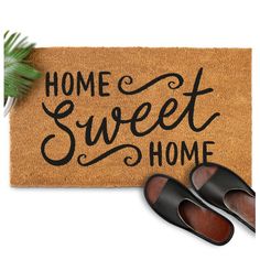 a pair of shoes sitting on top of a door mat that says home sweet home