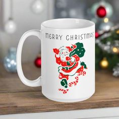 a white coffee mug sitting on top of a wooden table next to a christmas tree