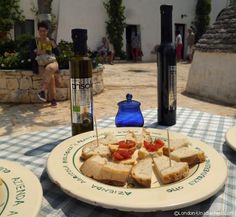 a plate with slices of bread and tomatoes on it next to two bottles of wine