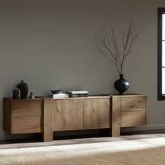 a wooden sideboard with two vases on top of it next to a window