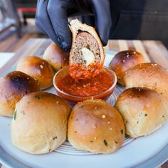 a plate topped with rolls covered in marinara sauce next to buns filled with meatballs