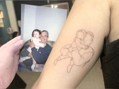 a person holding up a photo with a drawing on it's arm and the image of a baby in his arms